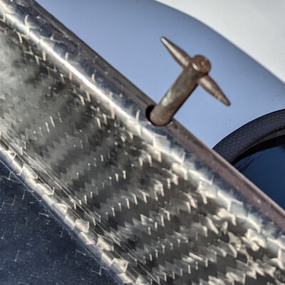 spiky protruding thumbscrew on a piece of carbon fiber